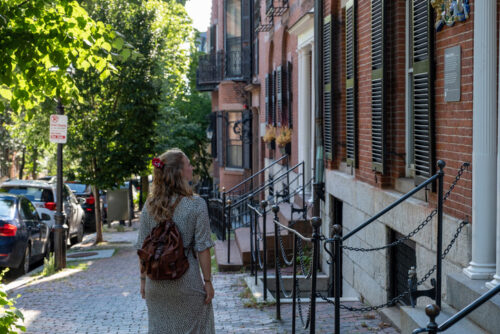Une voyageuse explore les rues historiques de Boston, Massachusetts, s'arrêtant devant une plaque commémorative sur une façade.