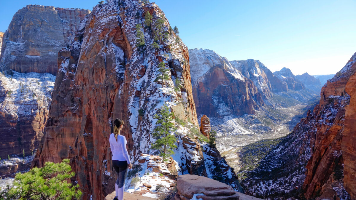 une jeune femme observe le parc national de zion sous la neige