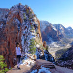 une jeune femme observe le parc national de zion sous la neige