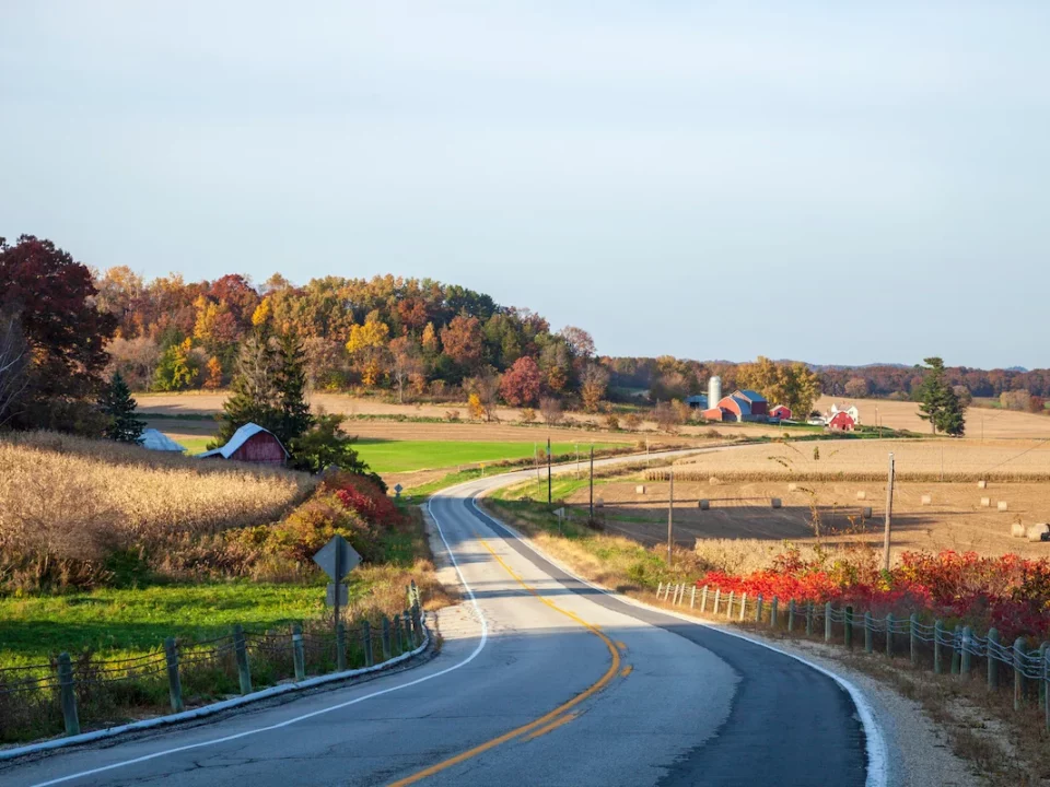 Route sillonnant la campagne dans le Wisconsin avec fermes rouges typiques de la région