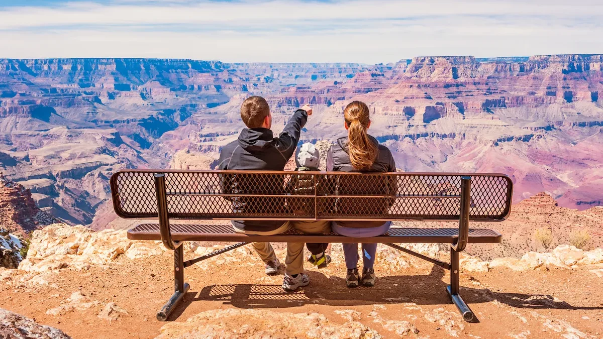 famille de dos assise sur un banc face au grand canyon