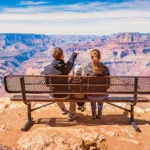 famille de dos assise sur un banc face au grand canyon