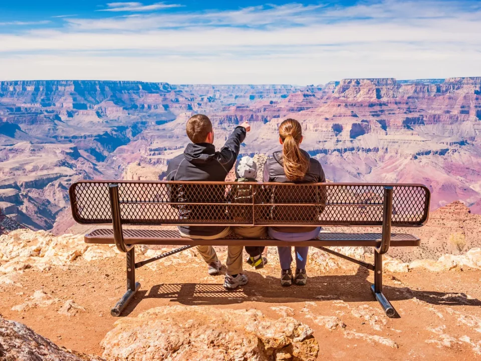 famille de dos assise sur un banc face au grand canyon